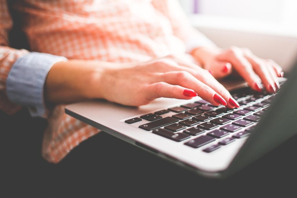 A pair of hands types on a laptop.