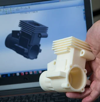 A finished 3D-printed object next to a computer screen displaying its design model.
