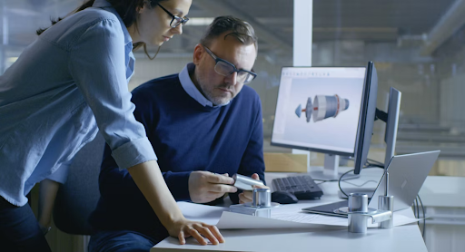 A man and a woman sit by a computer, looking over automation designs.