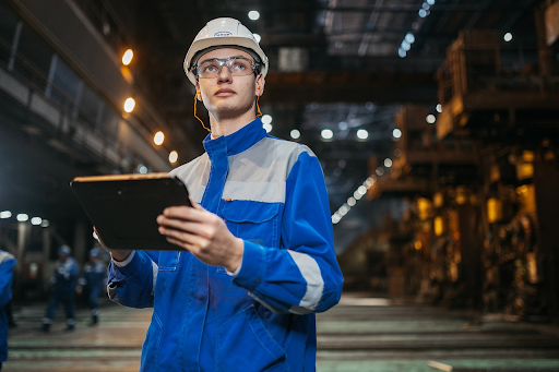 A man in protective gear oversees an industrial facility